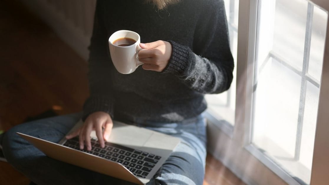 How to network as a freelancer image shows someone sitting with their laptop and a cup of coffee